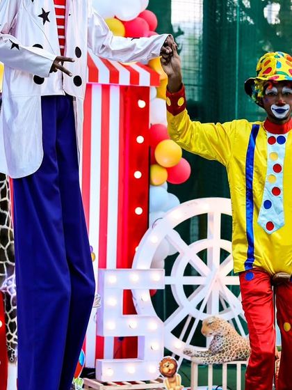 A clown and a stilt walker posing in front of the main stage, showcasing the professional entertainers I work with to elevate the party experience.