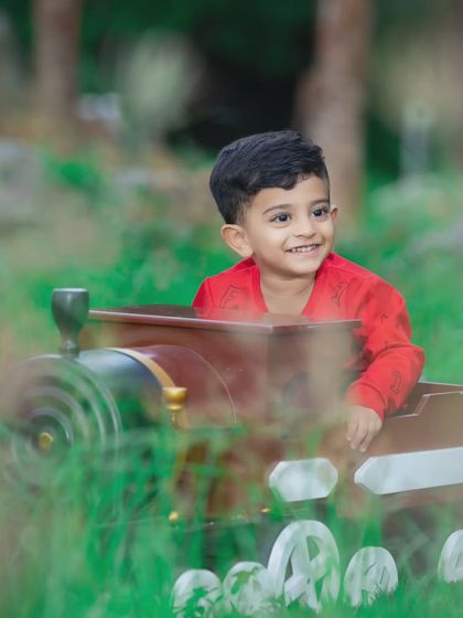 This little boy is enjoying an outdoor train ride, with a big smile on his face.