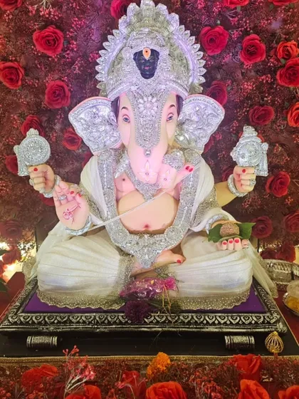 This image shows the fine details of the silver-adorned Ganpati idol against the vibrant red roses. The contrast between the silver and red makes the entire setup look incredibly rich and festive.
