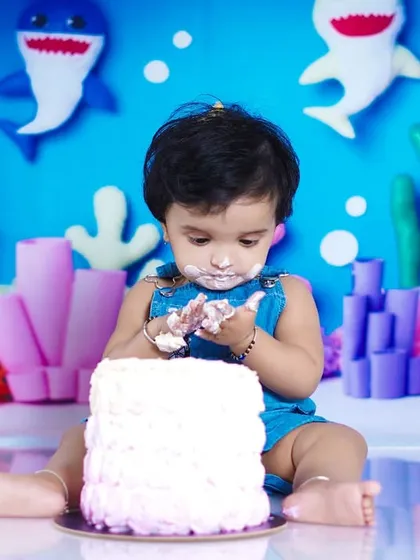 A close-up of the messy fun during a Baby Shark cake smash. This little one is enjoying every bit of his birthday cake.