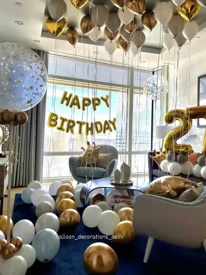 A bright and airy room decoration for a 21st birthday, with white, gold, and light blue balloons filling a modern living space.