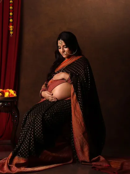 A serene and beautiful seated portrait, with the mama-to-be cradling her bump. The traditional decor adds to the timeless feel.