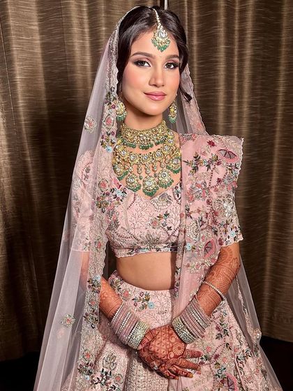 The full bridal look, showcasing the soft glam makeup with the pastel pink lehenga. The entire aesthetic is light, airy, and perfect for a modern daytime wedding.