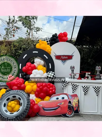 A fantastic Disney Cars themed party, featuring a Lightning McQueen cutout and a dessert table decorated like a pit stop. The backdrop includes a racetrack arch and checkered flag details.