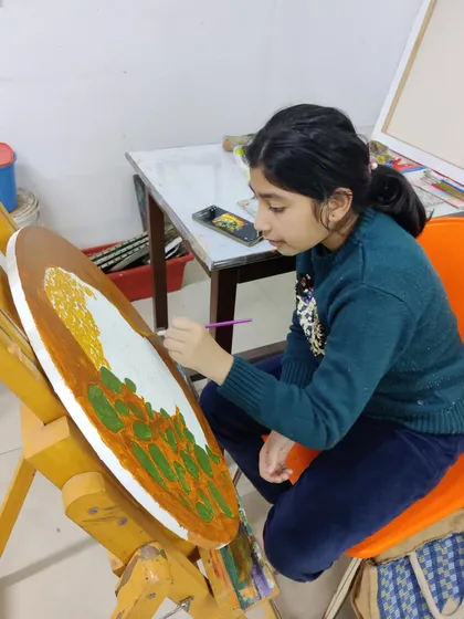 Multiple students are seen working on their own interpretations of Buddha paintings, showcasing a calm and focused studio environment.