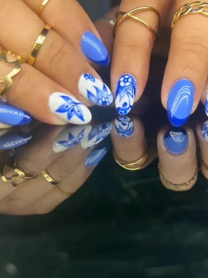A beautiful and intricate blue and white floral design, reminiscent of classic porcelain, on almond-shaped nails.