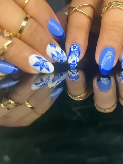 A beautiful and intricate blue and white floral design, reminiscent of classic porcelain, on almond-shaped nails.
