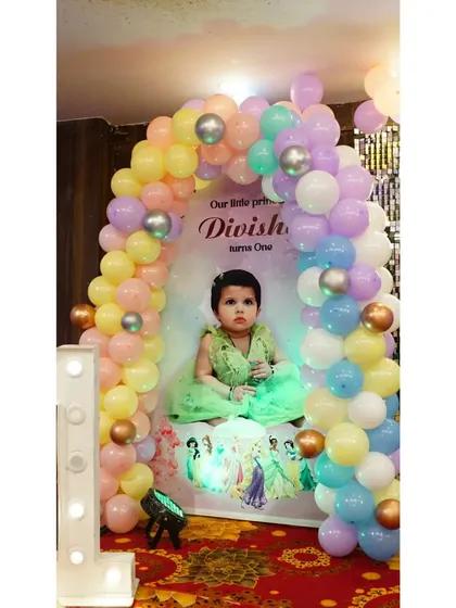A personalized photo backdrop is a wonderful touch for a first birthday. This one, framed by a pastel balloon arch, features a beautiful picture of the birthday girl, Divisha.