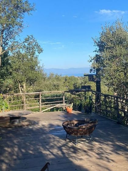 The spacious wooden deck at our Italy retreat location in Sardinia, surrounded by trees with a view of the sea. This is where we practice our morning asanas and evening meditation.