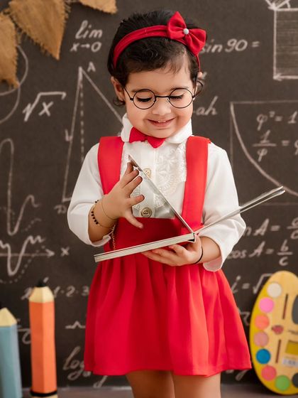 It's study time. This little scholar, with her glasses and red bow, looks so sweet as she curiously examines a book.