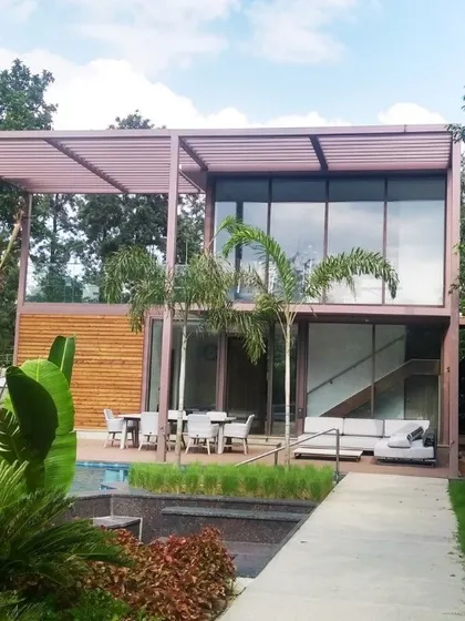 Another angle of the villa, showing how the structure sits within the landscape. The combination of the steel frame, wood panels, and extensive glass creates a lightweight, modern aesthetic.