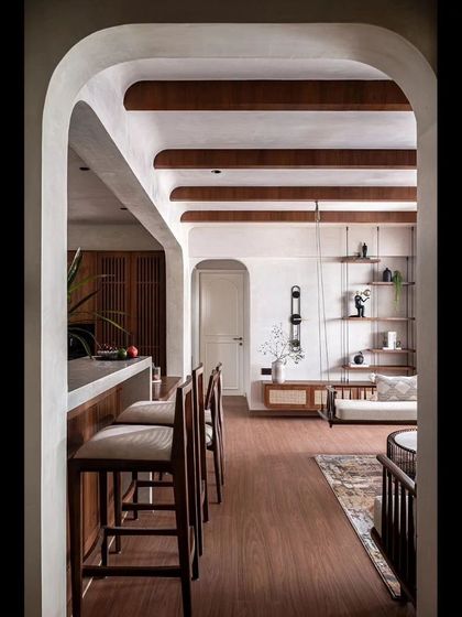 A view through an arched doorway reveals the open-plan living and dining area, with its cohesive palette of wood, white, and neutral tones.