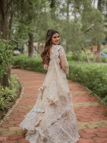 A lovely "look back" portrait of the bride as she walks through a green park. Her smile is infectious, and the shot beautifully captures the flow and detail of her white embroidered gown.