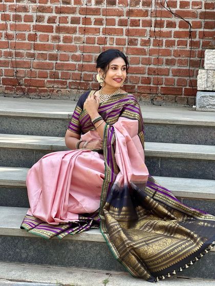 Seated on the steps, Chaitra shows off the beautiful fall of the saree and its rich, dark pallu. This is tradition reimagined.