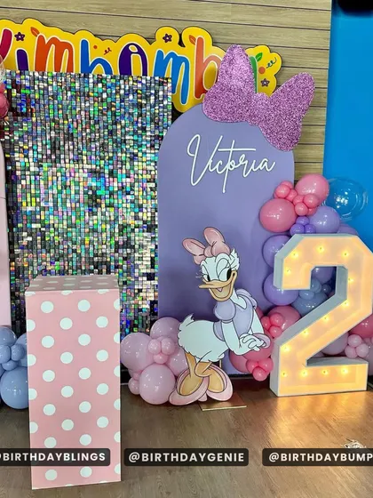 A close-up of the Daisy Duck side of the party, with a purple backdrop and a glittery Minnie Mouse bow accent.