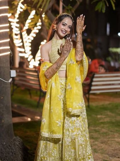 A full-length shot of the bride, dancing and celebrating at her mehendi night. Her henna-adorned hands are the perfect accessory to her beautiful yellow lehenga.