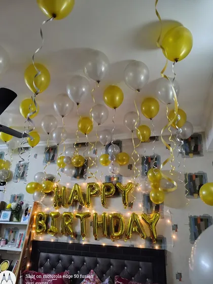 A wide shot of the room filled with yellow and white balloons. This shows how even a simple color scheme can completely transform a space for a birthday celebration.