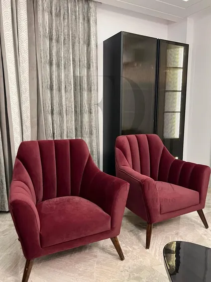 A pair of elegant armchairs in a rich, wine-red velvet. The channel-tufted backs and tapered wooden legs create a look that is both modern and reminiscent of mid-century design.