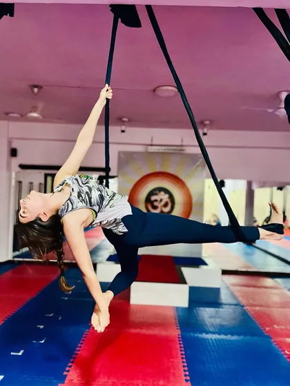 This graceful aerial pose, a variation of a side plank, builds incredible core and upper body strength. The student demonstrates focus and control while suspended.