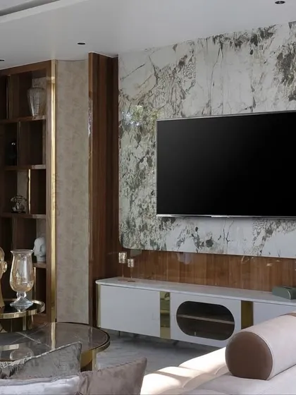 A detail of the TV unit, featuring a white console with gold accents set against a striking marble backdrop. This combination of materials creates a look that is both modern and luxurious.
