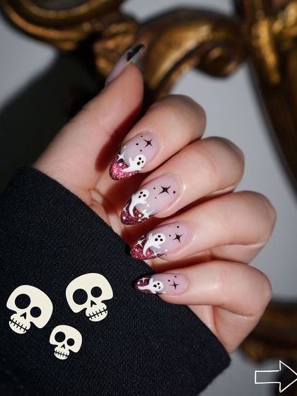 Hauntingly good Halloween nails. This spooky-cute design features little ghosts, stars, and a glittery pink tip for a fun and festive look.