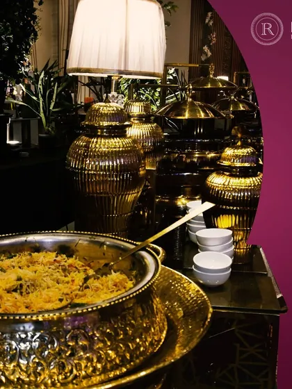 An opulent presentation of what appears to be a biryani or pulao in a grand, gold-finished serving bowl. Our bespoke catering services combine gourmet flavors with exquisite presentation.