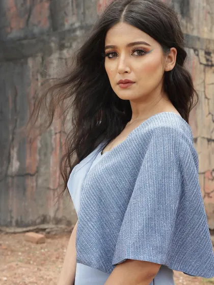 A closer portrait in the blue jumpsuit, focusing on the soft makeup and windswept hair that complement the outfit's gentle color and flow.