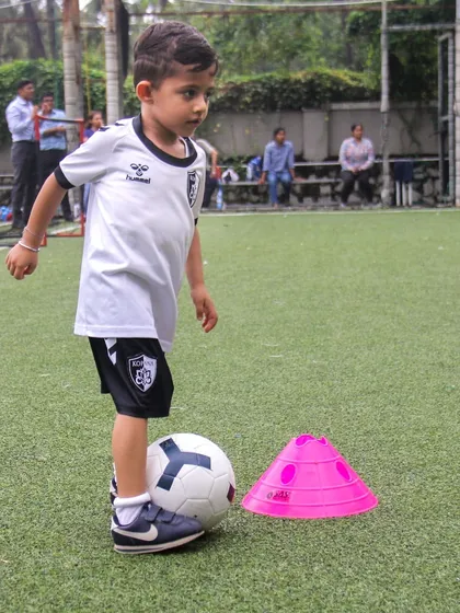 Even our youngest players learn the importance of close control. This U6 player carefully maneuvers the ball around a cone, building a strong foundation for future skills.