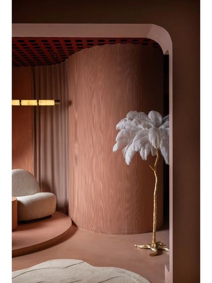 We love adding unexpected elements, like this whimsical feather floor lamp. It adds a touch of playfulness and texture against the wood-paneled curved wall and custom area rug.