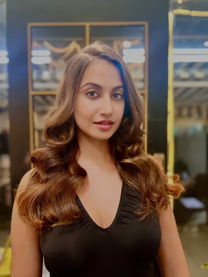 A beautiful example of a soft, voluminous style on brunette hair. The subtle highlights and bouncy curls create a look that is both glamorous and effortlessly chic.