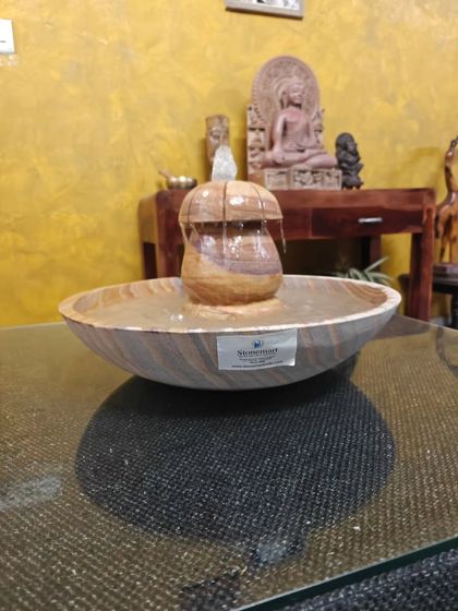 A close-up of the tabletop fountain, showing the water gently flowing over the carved stone.