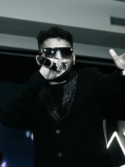 A high-contrast, black and white photo of a performer on stage. This artistic choice highlights the artist's expression and the intensity of the live show.