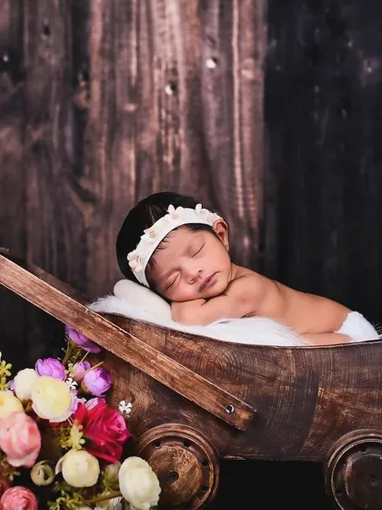 This peaceful newborn portrait highlights the tiny, delicate features of the baby. I use props like this rustic cart and soft flowers to add a touch of warmth.