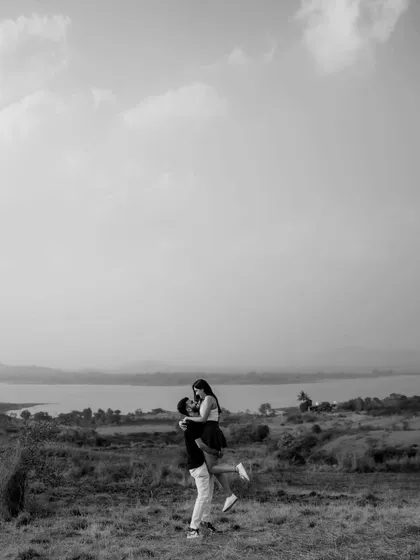 A wide shot that captures the feeling of freedom and joy. This black and white photo from a pre-wedding shoot shows the couple against a vast landscape, symbolizing the grand adventure they are about to embark on.