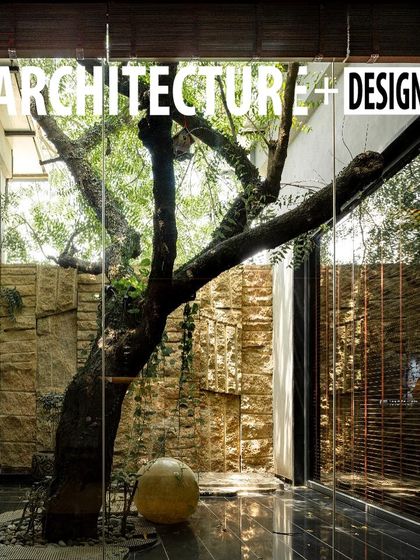 The cover of Architecture+Design magazine featuring the glass-enclosed courtyard at KEUS. This highlights the design philosophy of preserving nature within the built environment.