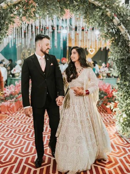The grand entrance as a newly married couple. Roop looks absolutely radiant in her white lehenga and elegant makeup.