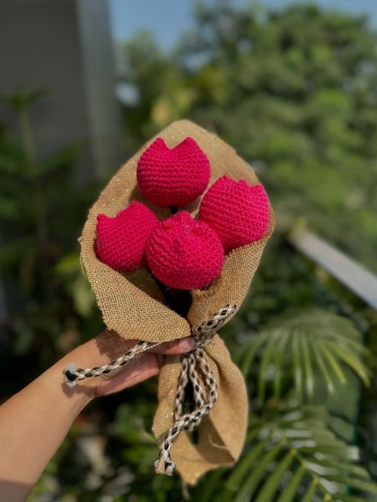 A bouquet of four bright pink crochet tulips. The vibrant color and beautiful craftsmanship make this a standout piece of decor.