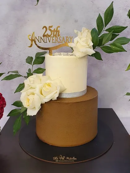 A closer look at the 25th-anniversary cake, highlighting the smooth finish and the elegant arrangement of white roses. The custom gold acrylic topper adds a personalized touch to celebrate this major milestone.