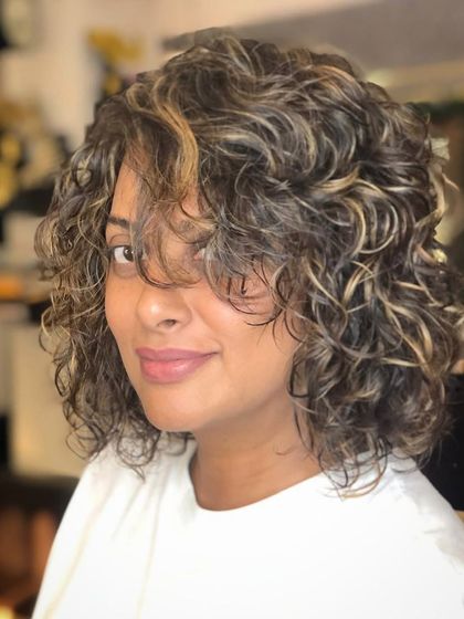 Adding blonde highlights is a fantastic way to brighten up curly hair. We carefully place the highlights to work with the curl pattern, ensuring they enhance the texture and create beautiful dimension without compromising the curls.