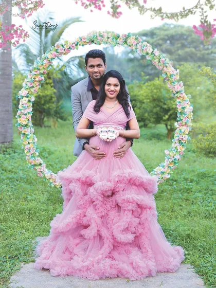 A beautiful outdoor couple portrait framed by a floral hoop. The pink ruffled gown adds a touch of romance to the lush green setting of my private outdoor location.