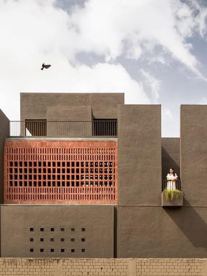 The west-facing facade of the 'H-House' features a crafted brick screen that filters the harsh sun, creating shifting shadows while ensuring privacy.