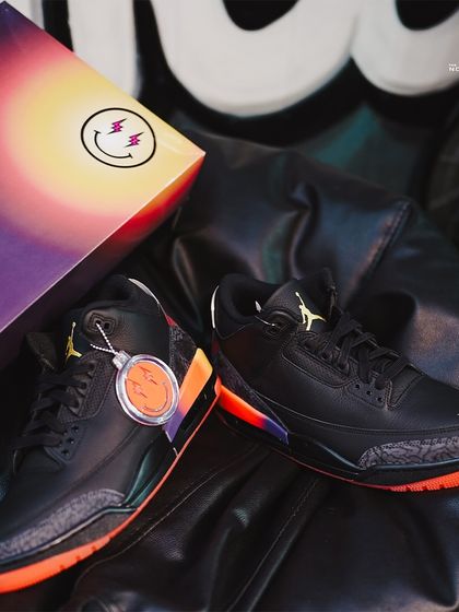The Jordan 3 J Balvin 'Rio' displayed with its special edition box. The box art itself is a collector's item, reflecting the sunset theme of the sneaker.