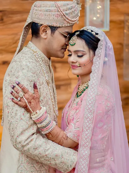 An intimate portrait of the couple. The bride's delicate makeup and soft pink lehenga create a dreamy, romantic vibe.