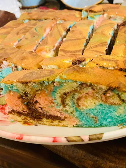 A close-up look at my ultra-moist ribbon cake. The colorful swirls of pink, blue, and chocolate are marbled through the fluffy cake, showing the soft texture and fun design in every slice.