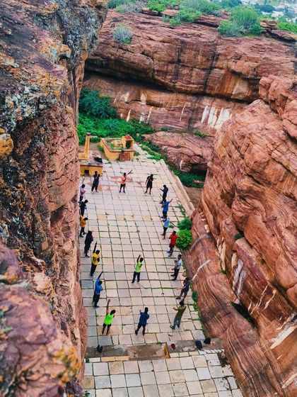Participants start their day with warm-up exercises in a stunning natural amphitheater formed by the cliffs of Badami.
