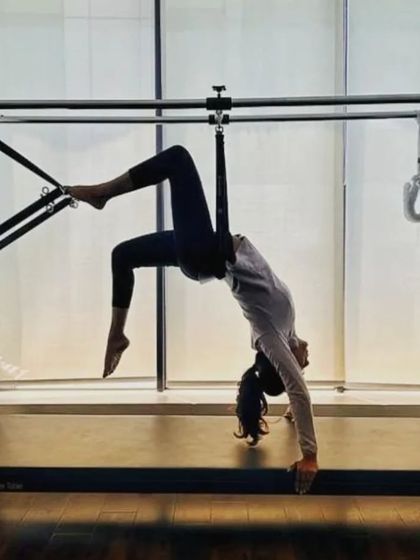 A client demonstrates an advanced stretch on the Cadillac, showcasing the incredible flexibility and control that can be achieved through consistent practice.