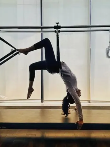 A client demonstrates an advanced stretch on the Cadillac, showcasing the incredible flexibility and control that can be achieved through consistent practice.