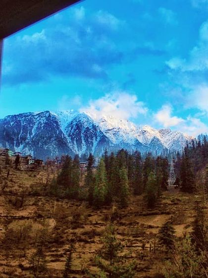 A view of the snow capped Himalayas from a window in a rustic wooden room. This frame captures the feeling of waking up to the mountains, a simple happiness that I find in Himachal.