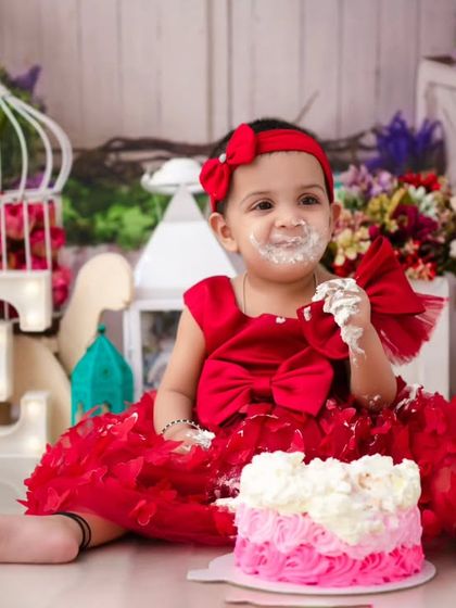 A sweet and messy smile. This close-up captures the pure happiness of a baby enjoying her birthday cake, a classic cake smash moment.