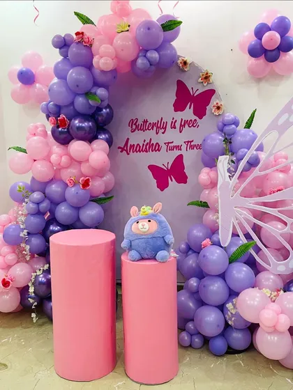 Another angle of the whimsical butterfly setup, highlighting the layered balloon arch and the cute plush toy placed on the cake stands.